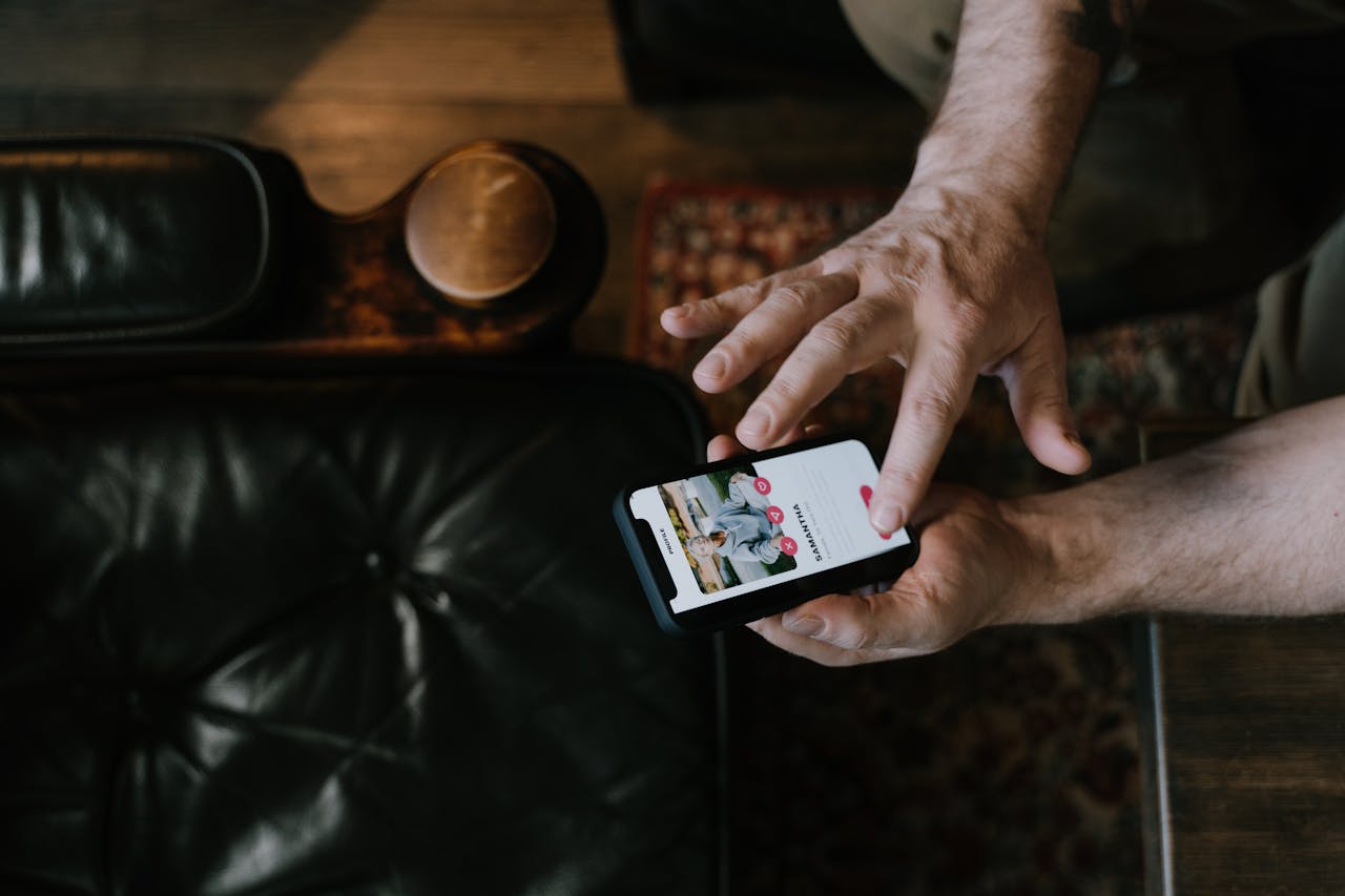 Overhead view of a man using a smartphone app while seated in a stylish room.